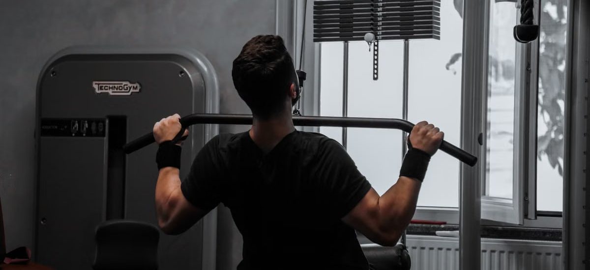 A man working out on a lat pulldown machine in a gym, focusing on strength building.